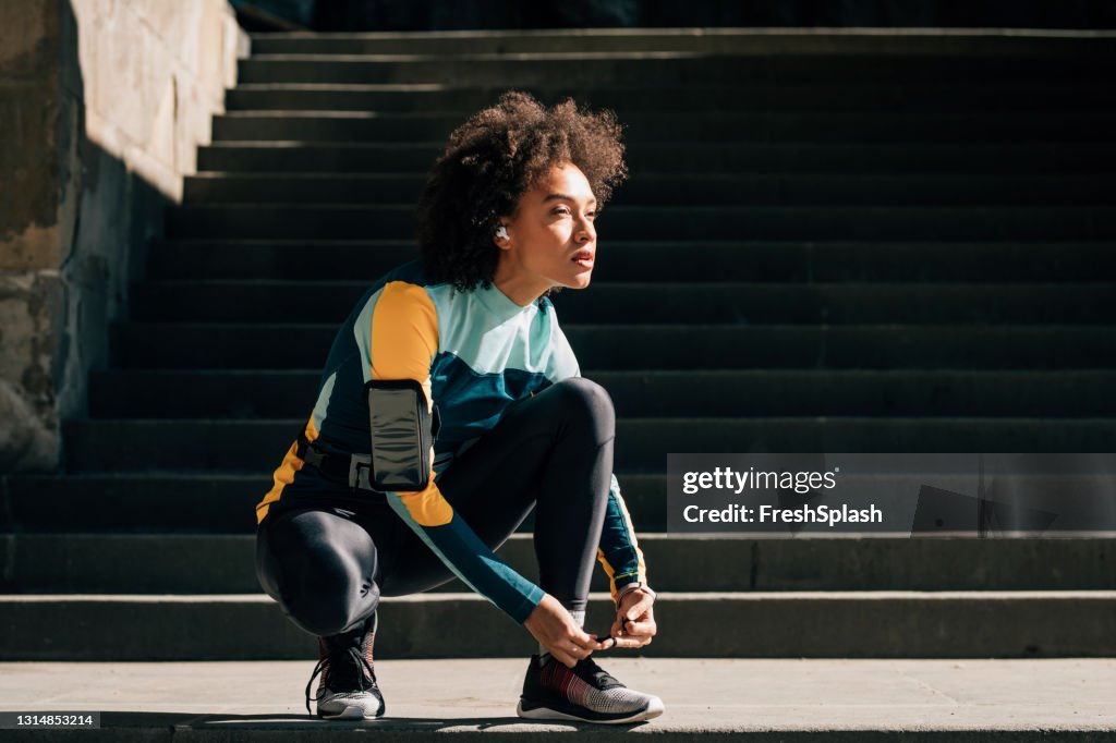 Confident Young Sportswoman Tying Her Shoelace, Exhausted from a Jog