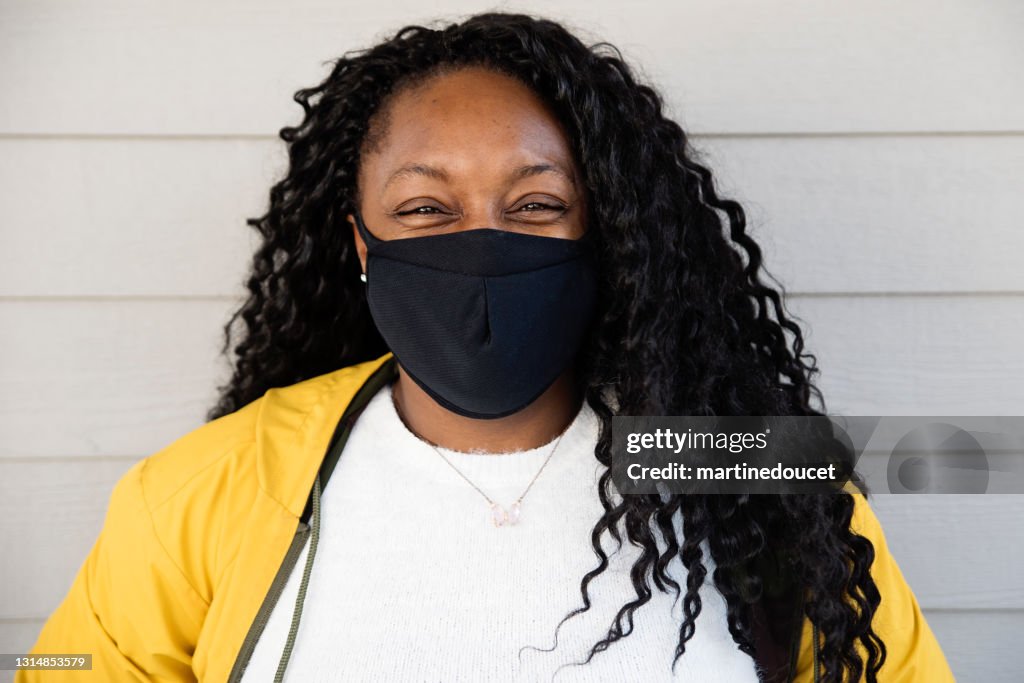 Woman smiling behind protective mask outdoors.