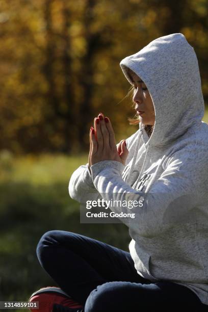 Christian woman praying in the forest. Autumn. France.