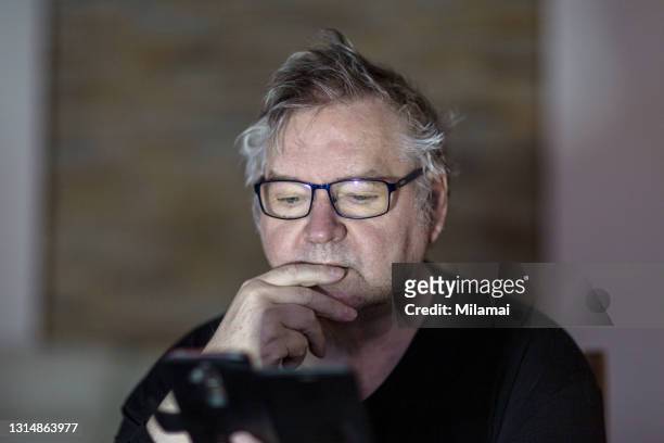 serious senior man alone using mobile phone and thinking about something - angry on phone stockfoto's en -beelden