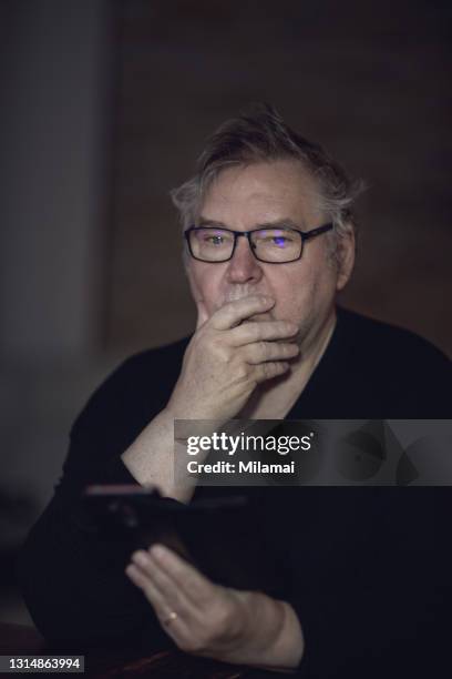 senior man alone using mobile phone and thinking about something, looking sad - man crying stock pictures, royalty-free photos & images