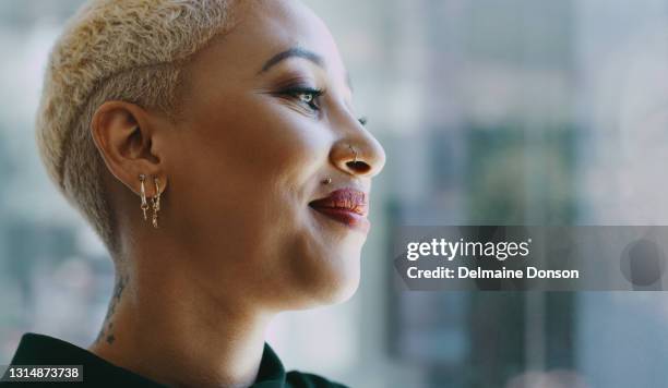 shot of a young businesswoman looking thoughtfully out a window in an office - piercing imagens e fotografias de stock