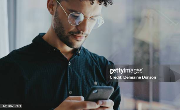 schuss eines jungen geschäftsmannes mit einem handy in einem büro - man texting stock-fotos und bilder