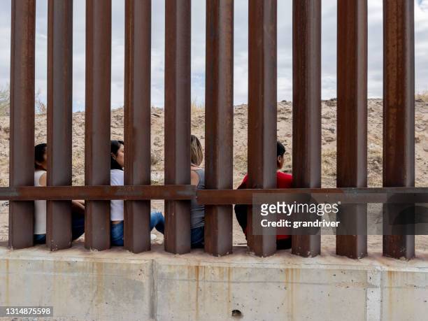 gruppe mexikaner, die die internationale grenzmauer zwischen chihuahua mexico und texas, usa, durchsehen - internationale grenze stock-fotos und bilder