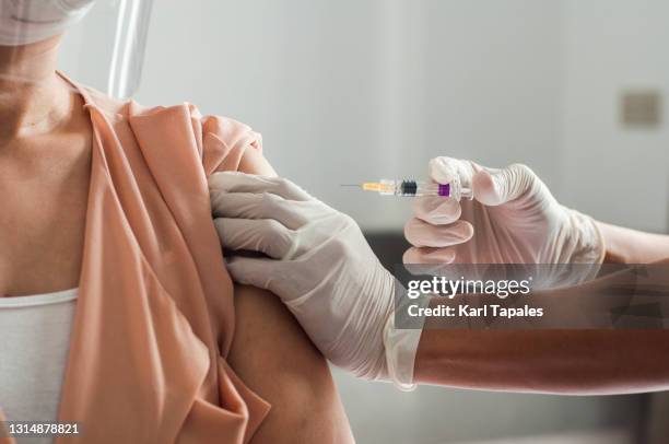 a male southeast asian medical frontline worker is vaccinating a female patient in the medical clinic - filipino stock pictures, royalty-free photos & images