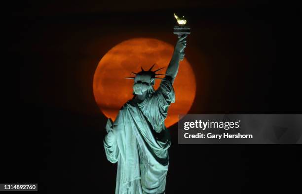 The pink moon rises above the Statue of Liberty in New York City a day after being full on April 27, 2021 as seen from Jersey City, New Jersey.