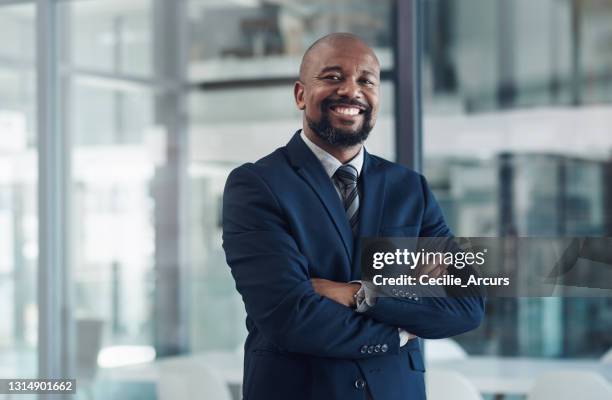 portrait of a mature businessman standing with his arms crossed in an office - man in black suit stock pictures, royalty-free photos & images