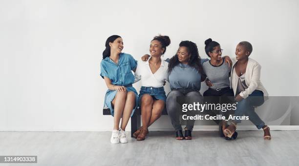 studio skott av en mångfaldig grupp kvinnor sitter tillsammans på en bänk - women for wallpaper bildbanksfoton och bilder