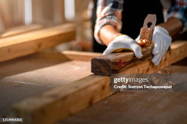 close up hands of a asian male carpenter holding a draw knife and trimming a plank - furniture maker foto e immagini stock