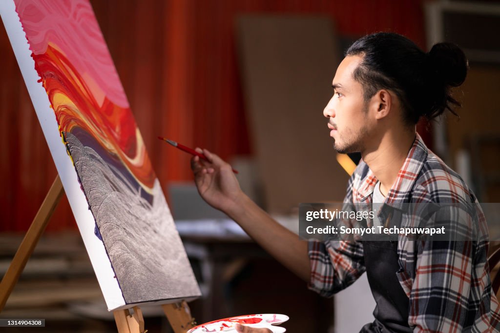 Young asian male woman paint drawing acrylic color on canvas at studio