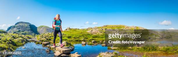 junge wanderin überquert gebirgsbach lake district panorama uk - stepping stone stock-fotos und bilder