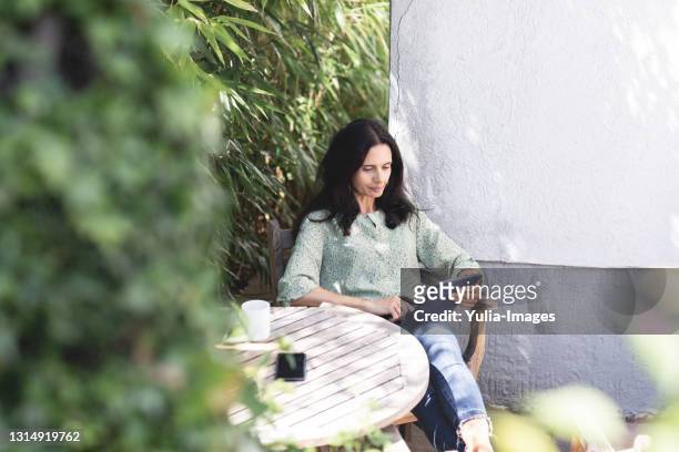 woman sitting working on a tablet pc outdoors - vacances plage stock-fotos und bilder