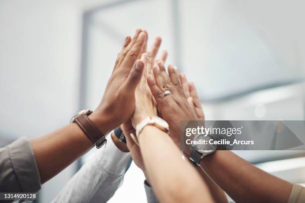 close-up die van een groep onherkenbare zakenlieden is ontsproten die hun handen in een huddle in een bureau verbinden - hi five stockfoto's en -beelden