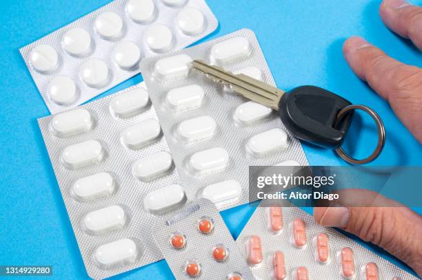 a person (man) picks up a car key that is next to pills. - ibuprofen stock-fotos und bilder