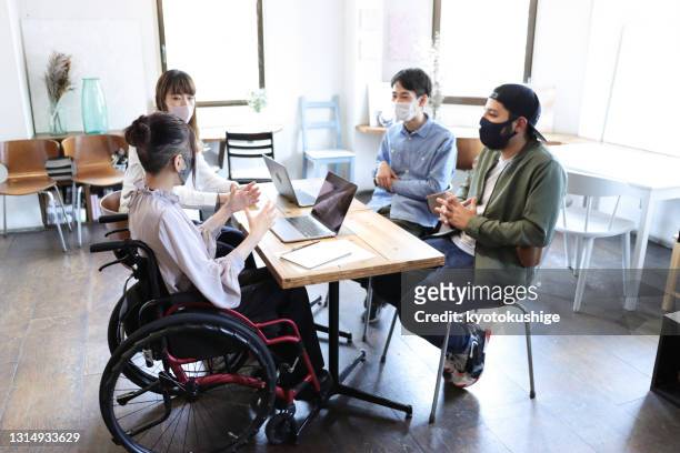 woman on wheelchair with her collegue at office - integración social fotografías e imágenes de stock