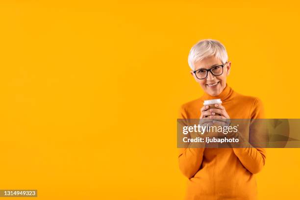 portret van glimlachende rijpe vrouw die beschikbare mok van koffie houdt - cup portraits stockfoto's en -beelden