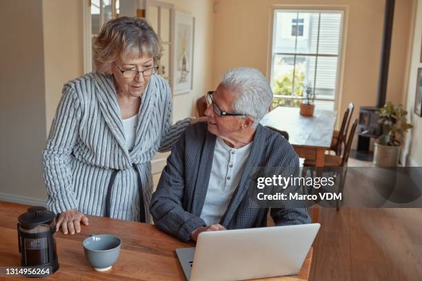 shot of a senior woman talking to her husband while he's busy on his laptop - debt free stock pictures, royalty-free photos & images