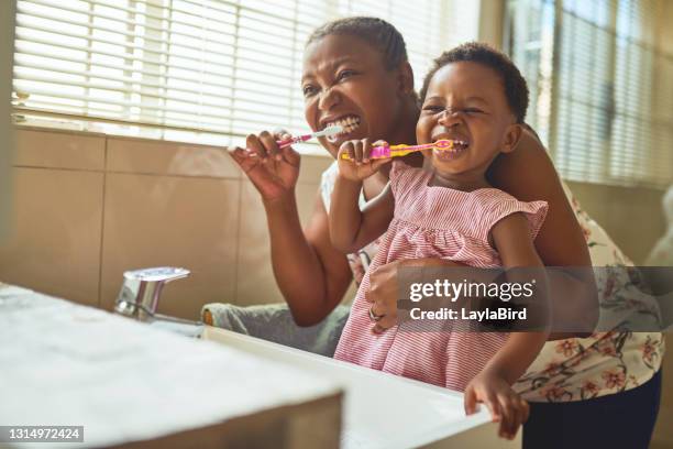 foto de una mujer y su hija cepillándose los dientes en casa - lavarse los dientes fotografías e imágenes de stock