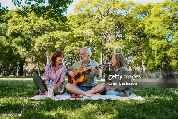 amigos mayores disfrutando en picnic con guitarra - plucking an instrument fotografías e imágenes de stock