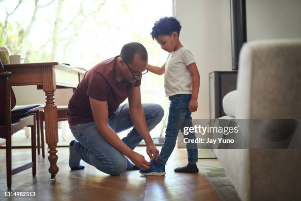 schuss eines vaters, der seinem sohn hilft, seine schnürsenkel zu hause zu binden - boy tying shoes stock-fotos und bilder