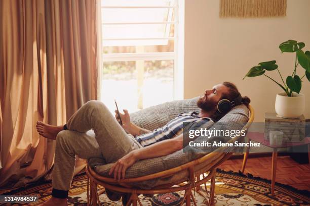 shot of a young man relaxing on a chair at home - lying down stock pictures, royalty-free photos & images