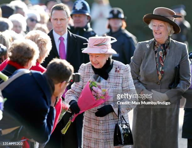 Queen Elizabeth II receives flowers from members of the public during a walkabout after attending Sunday service at the church of St Peter and St...