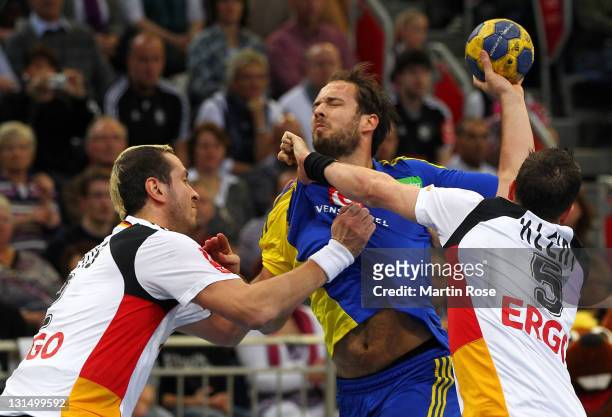Pascal Hens and Dominik Klein of Germany and Lukas Karlsson of Sweden compete for the ball during the Men's Handball Supercup match between Germany...