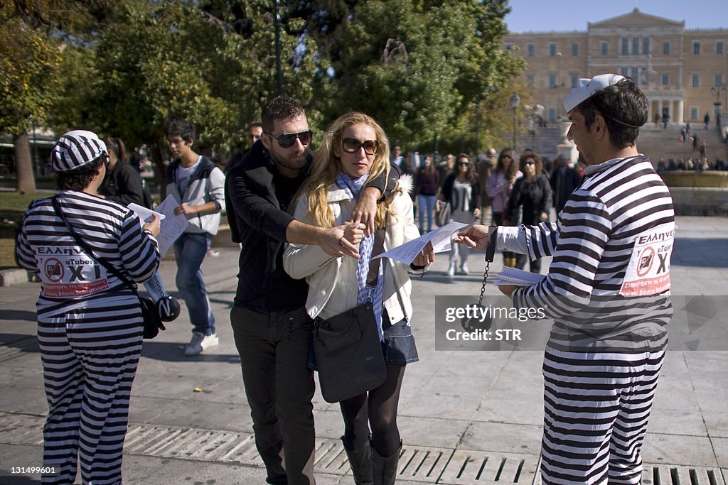 A couple walks past Greek demonstrators