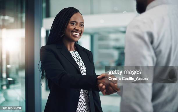 colpo di una giovane imprenditrice che stringe la mano a un collega in un ufficio moderno - popolo di discendenza africana foto e immagini stock