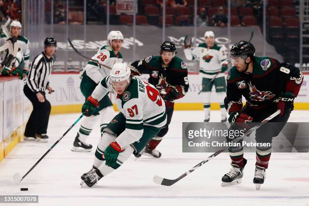 Kirill Kaprizov of the Minnesota Wild skates with the puck ahead of Nick Schmaltz of the Arizona Coyotes during the NHL game at Gila River Arena on...