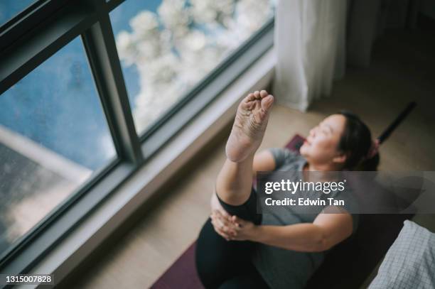 directly above asian chinese body -positive woman lying down on yoga mat workout at home during weekend - body lying down stock pictures, royalty-free photos & images