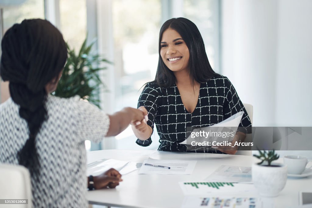 Shot of two young businesswomen shaking hands in a modern office