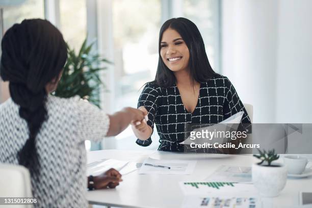shot of two young businesswomen shaking hands in a modern office - gerente imagens e fotografias de stock