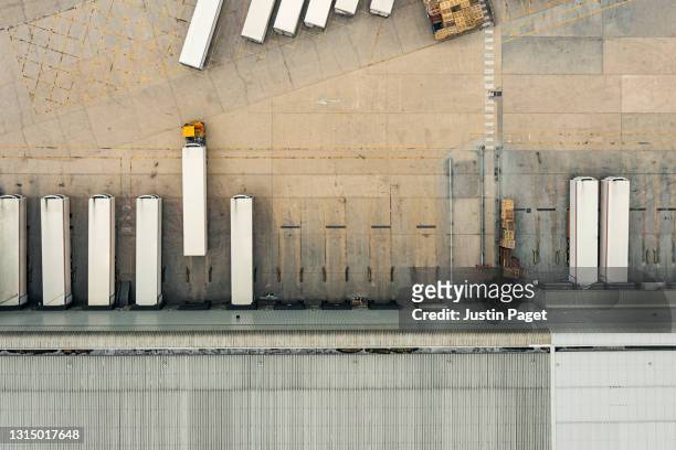drone view of a distribution warehouse with articulated lorries loading - freight transportation stock pictures, royalty-free photos & images