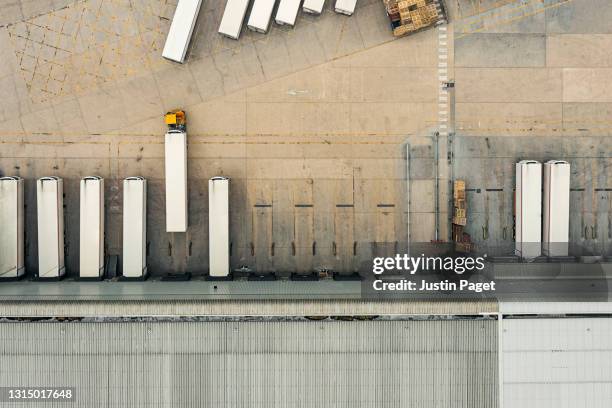 drone view of a distribution warehouse with articulated lorries loading - logistics stock pictures, royalty-free photos & images