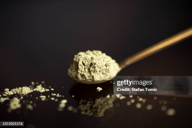 matcha tea powder on a spoon on dark background - powder tea stock pictures, royalty-free photos & images