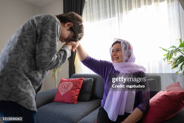 junge küssen großmutter hand bei religiösen fest - eid family stock-fotos und bilder