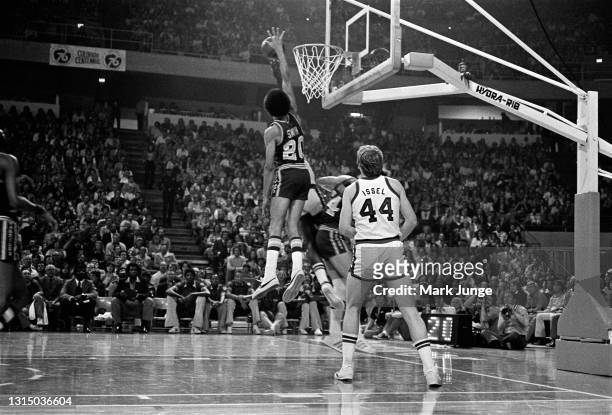 Denver Nuggets center Dan Issel watches as Golden State Warriors guard Phil Smith attempts to block a shot at the rim during an NBA basketball game...