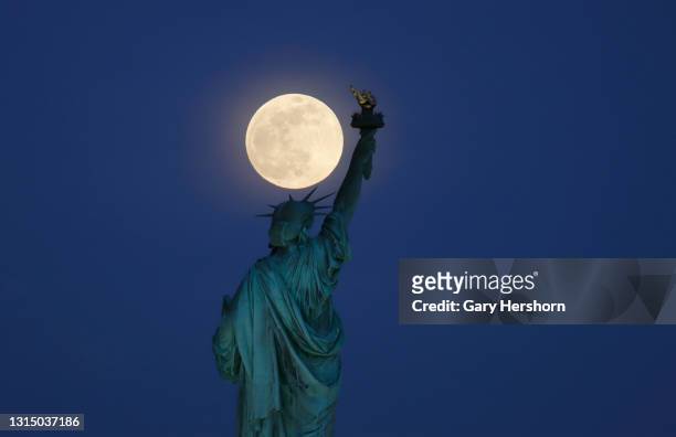The Super Pink Moon rises above the Statue of Liberty in New York City on April 26, 2021 as seen from Jersey City, New Jersey.