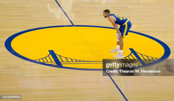 Stephen Curry of the Golden State Warriors stands at have court inside the logo and looks on against the Dallas Mavericks during the first half of an...