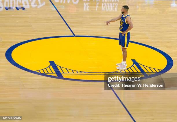 Stephen Curry of the Golden State Warriors stands at have court inside the logo and looks on against the Dallas Mavericks during the first half of an...