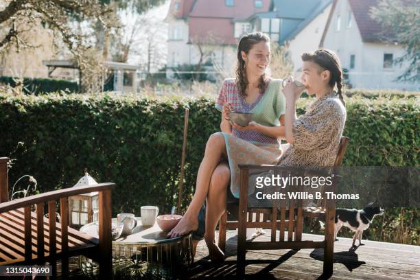 lesbian couple drinking coffee on decking in their garden - coffee on patio stock pictures, royalty-free photos & images