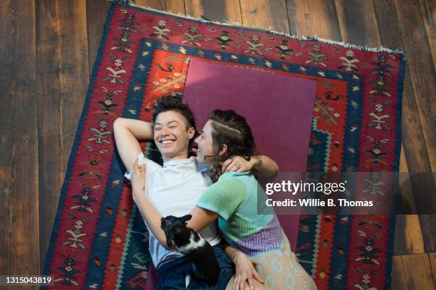 lesbian couple cuddling and laughing on the floor - lesbian date stock-fotos und bilder