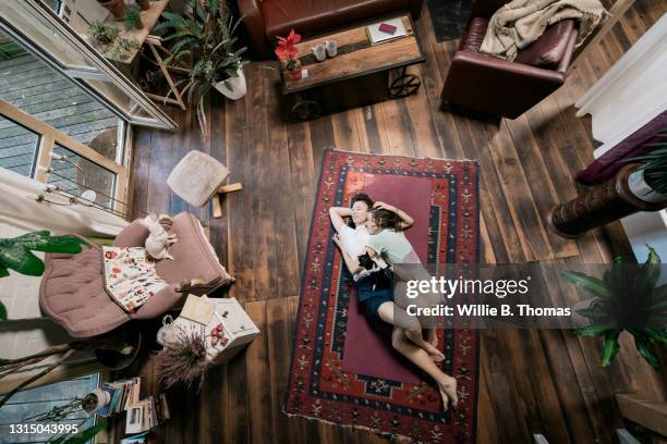 aerial view of lesbian couple cuddling on living room floor - comfortable couple stock pictures, royalty-free photos & images