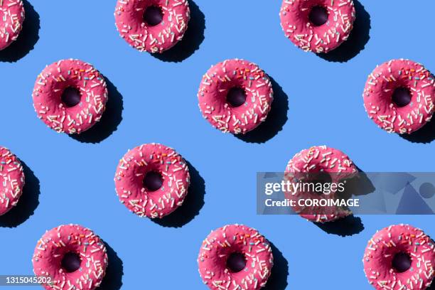 pink doughnut on pastel blue background. chewed donut. - donut stock-fotos und bilder