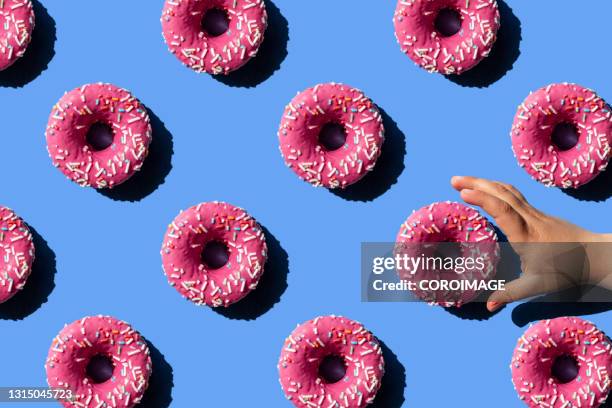 pink doughnut on pastel blue background. child's hand holding a donut. - take out food imagens e fotografias de stock