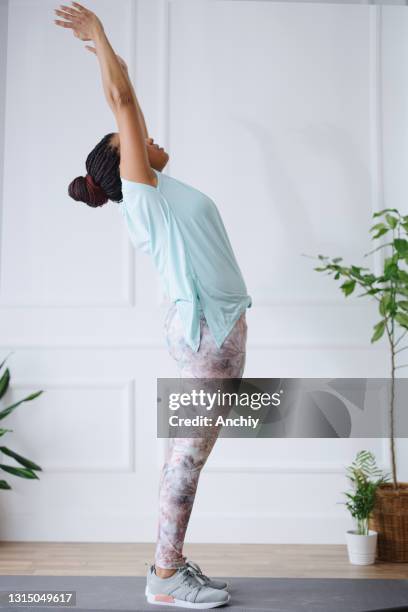 woman practicing yoga at her home using digital tablet to watch exercises - sun salutation stock pictures, royalty-free photos & images