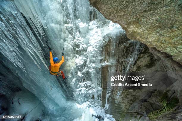 luftperspektive des eiskletterers, der einen gefrorenen wasserfall in canyon aufsteigt - frozen waterfall stock-fotos und bilder