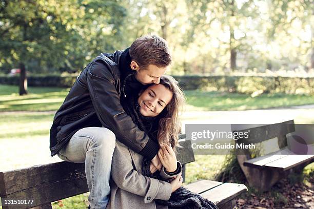 young couple sitting on bench outdoor. - verliefd worden stockfoto's en -beelden
