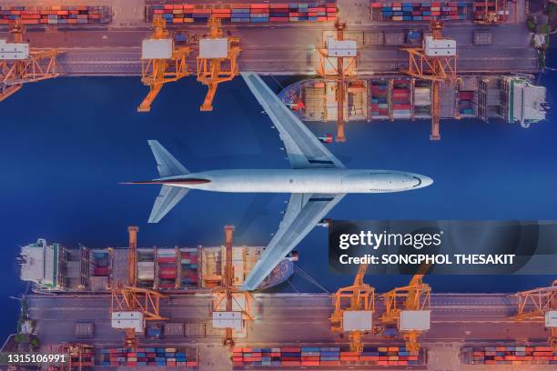 aerial view/an aircraft flying over a port carrying containers onto a cargo ship for delivery to the country of destination. - air freight transportation stock pictures, royalty-free photos & images